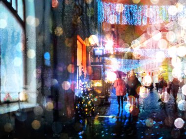 Şehir, yağmurlu Noel tatillerinde aydınlık geceyi bulanıklaştırdı sokak dekorasyonu insanlar şemsiyelerin altında yürüyorlar şehir arka planında 