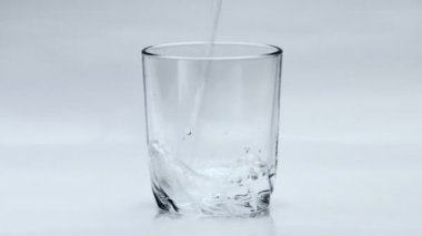 Beyaz arka plan üzerinde şeffaf cam içine su dökme