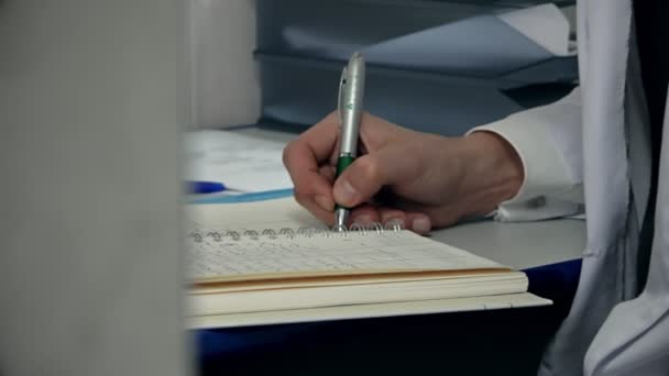 Человек в белом халате пишет вымышленные русские имена с шариковой ручкой в — стоковое видео