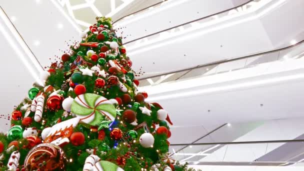 Grote versierde kerstboom in het winkelcentrum van meerdere verdiepingen flikkert met — Stockvideo