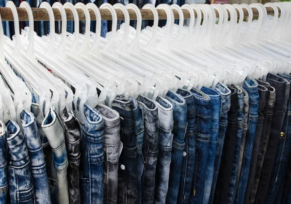 Jeans auf Kleiderbügeln im Hintergrund des Marktes — Stockfoto