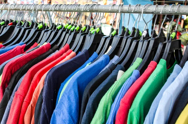 Buntes T-Shirt auf Kleiderbügeln auf dem Wochenmarkt. — Stockfoto