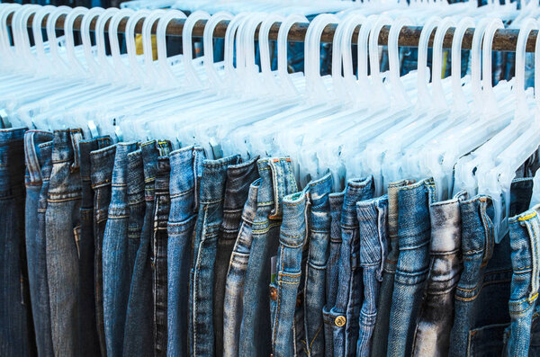 Row of Jeans and trousers on hangers for sale