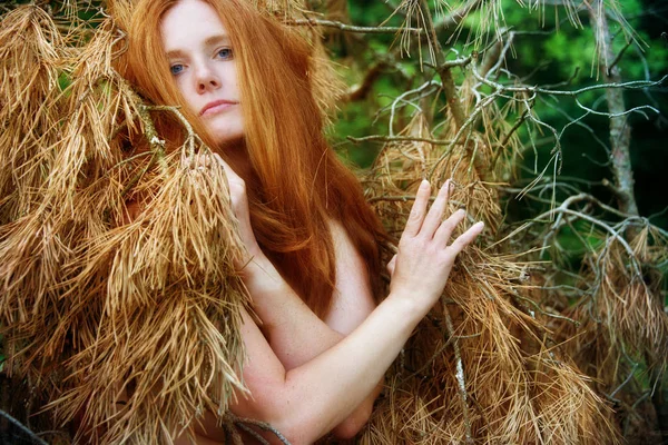 Krásná zrzka žena v borovicové větvi se suchými jehličkami. — Stock fotografie
