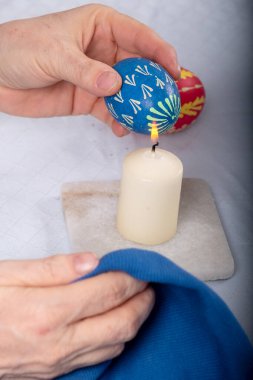 Mavi renkli Paskalya yumurtasının Sorbiya geleneğine göre kadınların elleri mumu yakıyor.