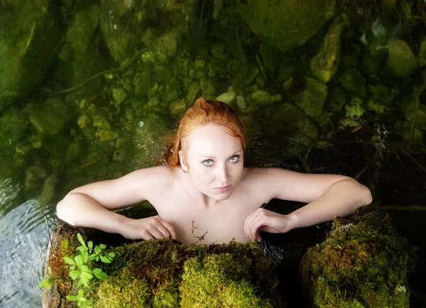 性感的年轻性感的红头发美人鱼被卡在一个被挖空的树干里 敏锐地引诱着 在水里 池塘里 沼泽地里放着粉红的睡莲 — 图库照片