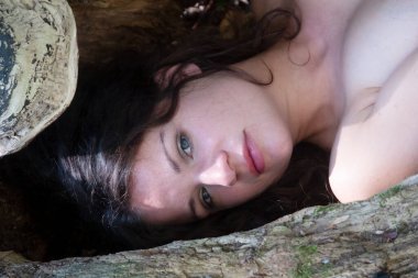 Güzel, siyah saçlı, seksi bir kadının portresi. Mutlu bir şekilde uzanıyor ormanda. Yaşlı bir söğüt ağacında.