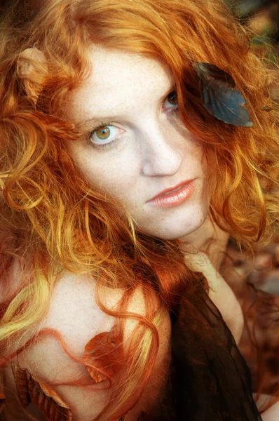 Portrait of a cute young lovely redhead girl with red and orange autumnal leaves. Beautiful face of a young sexy woman among red golden foliage.