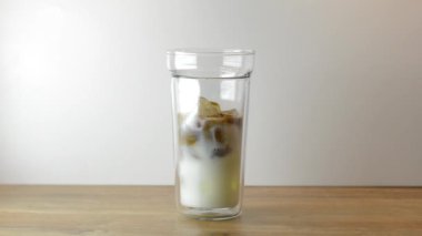 Hafif ahşap masada buzlu süte kahve doldurmak, stüdyoda çekim yapmak. Turk kahve içmek için, sütlü bir bardak doldurmak. Buzlu kahve yapmak..