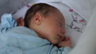 Yeni doğan çocuk bebek arabasında yatıyor, gözleri kapalı uyuyor. Bebek doğduğunda hayatın ilk anları
