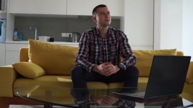 Rahat bir odada kanepede oturan kendine güvenen ve odaklanmış serbest çalışan bir genç. Başarılı, düşünceli, bin yıllık bir adam.