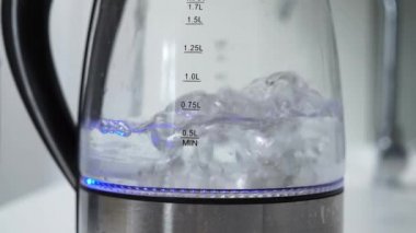 Akıllı bir ev dairesinin modern, yüksek teknolojili mutfağında cam şeffaf elektrikli sıcak su demliği. Su çay ya da kahve yapmak için kaynatılır. Büyük kabarcıklar