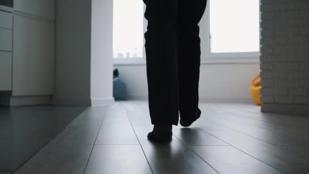 Männerbeine in Socken gehen auf den Fliesen durch die moderne Loft-Wohnung auf den Balkon vor der Kamera. — Stockvideo