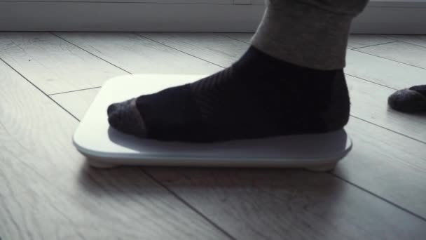 Mens benen gekleed in broek en sokken zijn op elektronische schalen. Body mass control tijdens het verliezen van gewicht. Dagelijkse gewichtmeting, lichaamsverzorging. Gezondheid en welzijn — Stockvideo