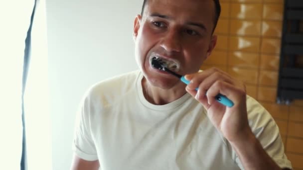 Giovane uomo spazzolatura denti in bagno davanti allo specchio. Fare igiene di routine guardarsi allo specchio. Cura orale dentale al mattino . — Video Stock