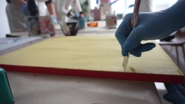 The artist scratches the paint with a spatula. Paint cans. Yellow paint. — Stok video