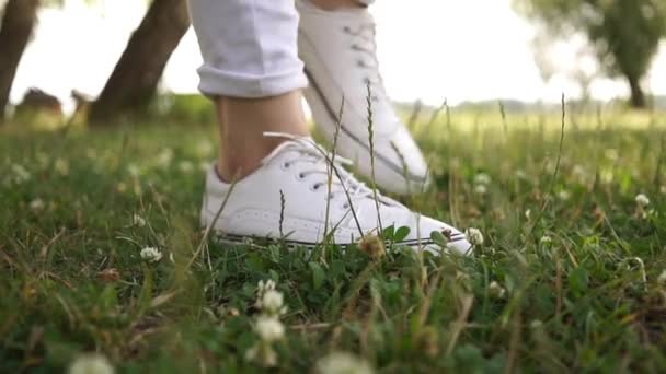 Weiblicher Fuß in weißen Turnschuhen tritt auf einem morgendlichen Lauf auf das Kleefeld im grünen Gras — Stockvideo