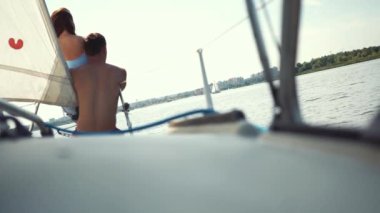 Romantik mutlu çift güneşli yaz gününde yat pruvasında yelken açıp dinleniyorlar. Balayı. Yolculuk. Yaz tatilleri. Seyahat yerleri. Deniz yolculuğu ve yelkenli yarışı.