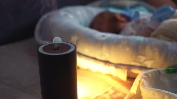 Vapeur d'un humidificateur devant bébé endormi. Humidificateur noir humidifie l'air sec. Améliorer le confort et le bien-être des personnes. Dispositif climatique. Prévention des maladies respiratoires. — Video