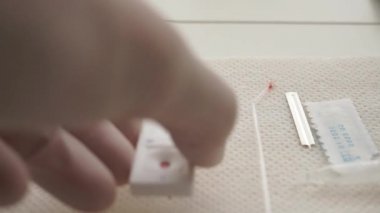 Beyaz eldivenli bir el peçeteye hızlı bir koronavirüs testi uygular. Test sonuçları pozitif. COVID-19. Kan testi malzemeleri. Yakın plan. iki şerit
