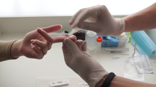 Een arts die handschoenen draagt, neemt bloed van een vinger voor analyse van een vrouwelijke patiënt. Close-up opname — Stockvideo