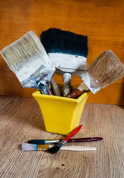 Old brushes in a yellow vase — Stock Photo, Image