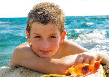  Denizin arka planında genç yüzücü kayaüzerinde yüzmek için gözlük ile elini koydu. 