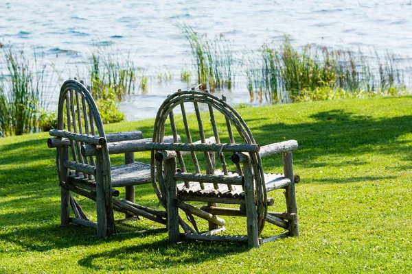 Dvě staré dřevěné židle stojí na zeleném trávníku — Stock fotografie