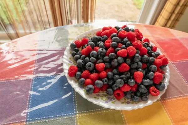 Plate on the table with fresh raspberries and blueberries — Stock Photo, Image