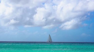 Sailing yacht sailing on the horizon of the Caribbean against the blue sky under white clouds