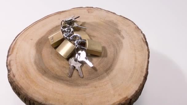 スチールキーを持つ小さな青銅製のロックは 木の丸みを帯び 白い背景に時計回りに回転します — ストック動画