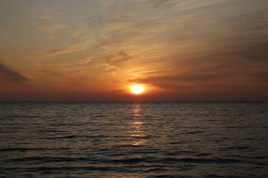 Denizin üzerinde güzel, parlak bir gün batımı. Suda yansıması var..