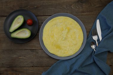 Omlet, omlet ve avokado, ahşap arka planda domates peçete, kaşık, çatal, bıçak. Üst Manzara Düz Yatıyordu. Menü için fotoğraf. Yemek arkaplanı, desen, poster. Uzayı metin için kopyala. Fotoğraf menüsü.