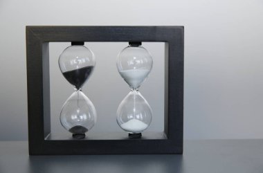 Gri arka planda ahşap bir çerçevede kum saati. Zaman kavramı. Metin için kopyalama alanı ile.