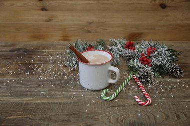 Noel kompozisyonu bir kupa kakao çikolata, karamel şeker kamışı ve ahşap arka planda metin için fotokopi alanı olan süslemeler..