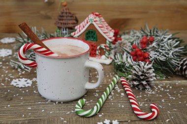 Yakın plan Noel kompozisyonu zencefilli kurabiye evi, bir kupa kakao çikolata, karamelli şeker kamışları zencefilli kurabiye evi ve ahşap arka planda metin için fotokopi alanı olan dekorasyonlar..