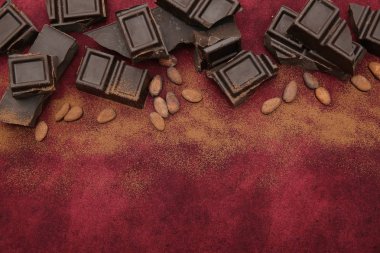 Kakao çekirdeği ve kakao tozu ile kaplanmış koyu çikolata kırmızı arka planda fotokopi alanı ile. Şekerleme malzemesi. Arkaplan, desen, kartpostal, menü düz üst görünüm. Sevgililer günü, Noel, hediye