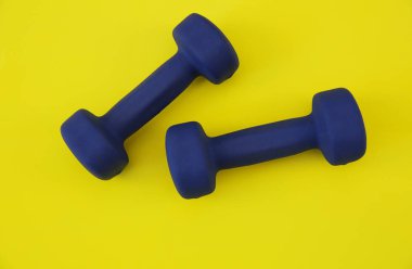 Sarı arka planda mavi halterler izole edilmiş. Fitness, spor salonu ve sağlıklı yaşam tarzı. Üst Manzara. Düz yatıyordu. Uzayı metin için kopyala. Arkaplan, kalıp, pankart.