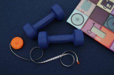 Mavi arka planda bant ölçüsü ve elektronik pullu mavi halterler. Fitness, spor salonu ve sağlıklı yaşam tarzı. Kilolu biriyle dövüşmek. Arkaplan, kalıp, pankart.