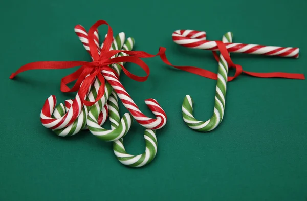 Pile Candy sugar canes tied with a red ribbon on a green background. Christmas background. Concept of Christmas and New Year. Caramel sugar cane concept Copy space. Close-up. Pattern, card, frame.