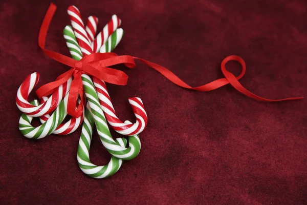 Pile Caramel sugar canes tied with a red ribbon on a red background. Christmas background. Concept of Christmas and New Year. Caramel sugar cane concept Copy space. Close-up. Pattern, card, frame.