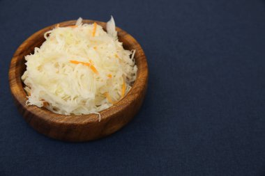 Lezzetli lahana turşusu ya da mayalanmış lahana, mavi arka planda izole edilmiş ahşap bir kasede. Mayalanmış yiyecek. Bigolar için malzeme. Metin için kopyalama alanı ile.