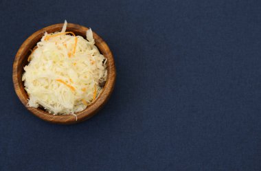 Lezzetli lahana turşusu ya da mayalanmış lahana, mavi arka planda izole edilmiş ahşap bir kasede. Mayalanmış yiyecek. Bigolar için malzeme. Metin için kopyalama alanı ile. Düz yatıyordu. Üst görünüm.