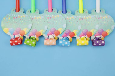 Tatil arkaplanı mavi üzerine renkli düdükler. Tatil ve doğum günleri kavramı. Düz yatıyordu. Üst Manzara. Boşluğu kopyala.