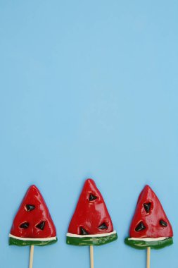 Mavi arka planda izole edilmiş karpuz şeklinde lolipoplar. Şekerleme arka planı. Tatil ve hediye kavramı. Üst Manzara. Düz yatıyordu. Metin için kopyalama alanı ile.