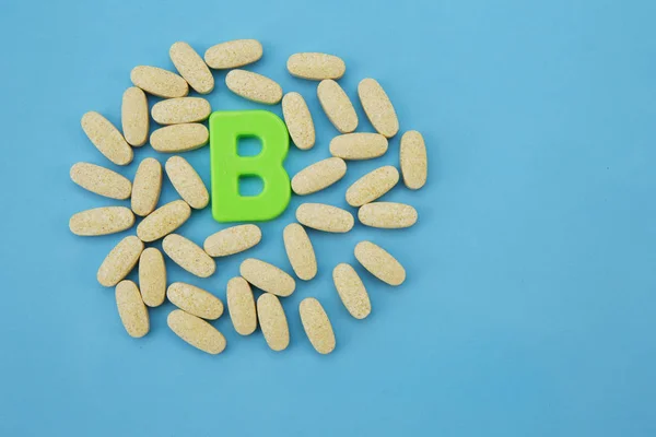 Vitamin B in pills with the letter B on a blue background. Flat lay. Top view. Copy space.