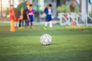 Yeşil suni sahada futbol topu ve bulanık çocuk futbolu.