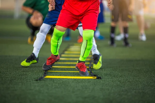 Dětští fotbalisté jsou jogging a skok mezi značkou pro nohy — Stock fotografie