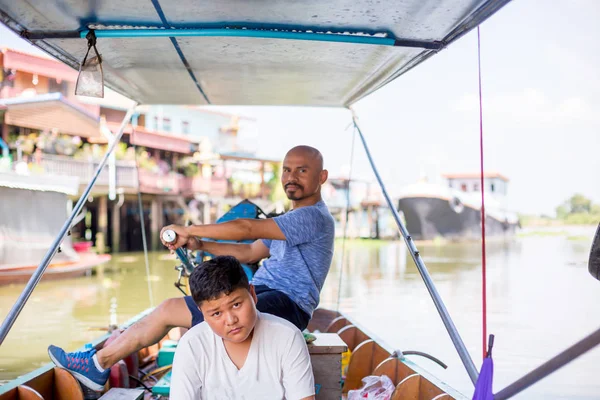 Asian father drive a long-tail boat with son to travel on a natu