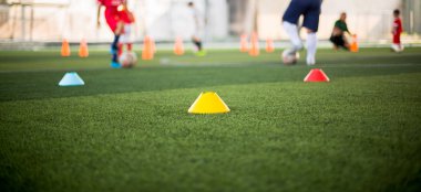 Bulanık çocuk futbol oynayan yeşil yapay çim üzerinde işaret konisi